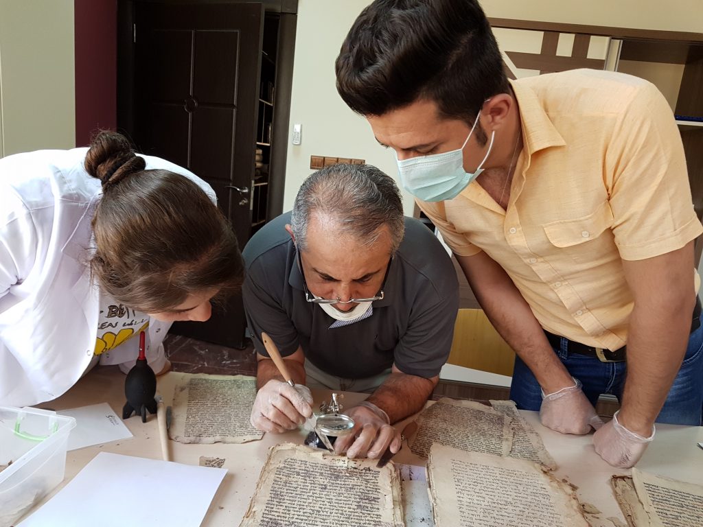 Technicians with Fr. Najeeb (center) examining a manuscript at CNMO, Erbil