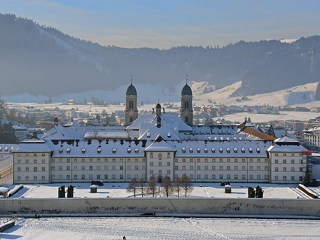 Einsiedeln. Photo by <a href='https://commons.wikimedia.org/wiki/User:Roland_zh'>Roland zh</a> on <a href='https://commons.wikimedia.org/wiki/File:Einsiedeln_-_Kloster_2013-01-26_13-50-51_(P7700).JPG'>Wikimedia Commons</a>, (CC BY-SA 3.0)